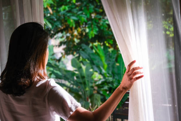 窓から外を眺める女性